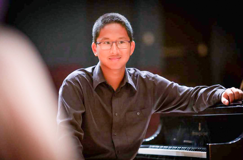 male student sitting at the piano
